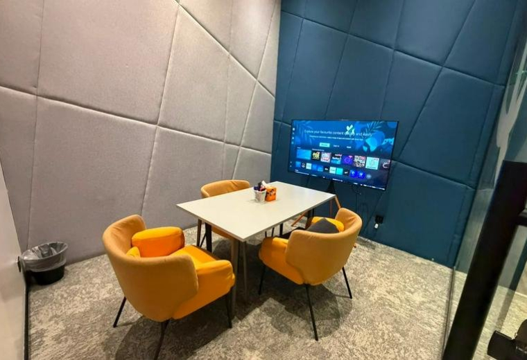 Private meeting room at Prince Sultan Road with yellow armchairs and a wall-mounted TV.