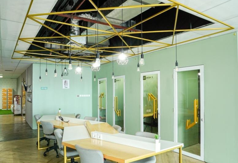 Spacious coworking area at Harton Tower with modern geometric ceiling art and light green walls.
