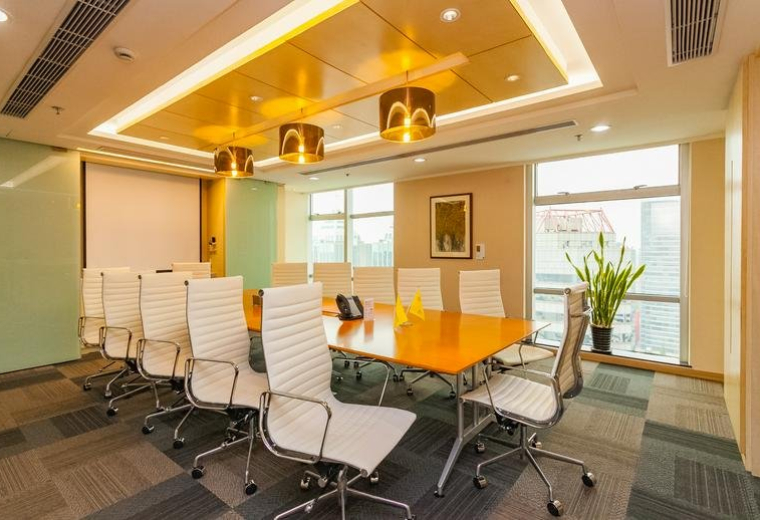 Spacious boardroom with a large wood table, white chairs, and elegant pendant lighting.