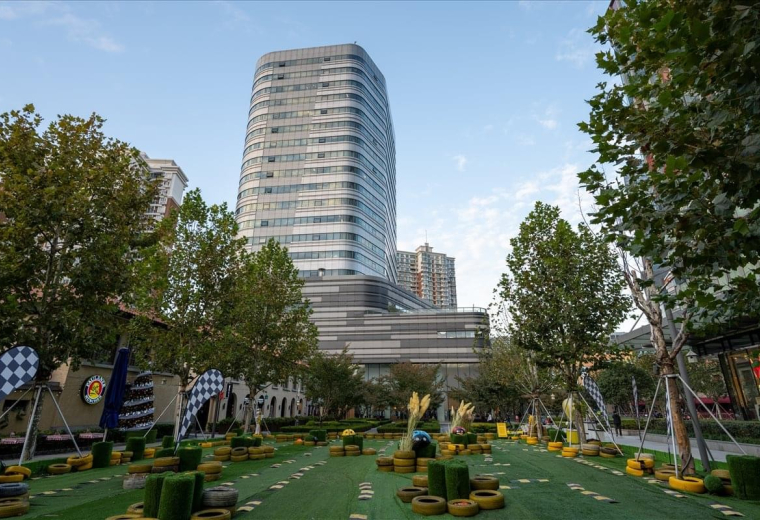 Exterior view of the modern glass skyscraper at 1193 Changning Road surrounded by green space.
