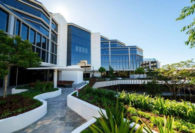 External facade of the office building featuring tiered glass windows and lush gardens.
