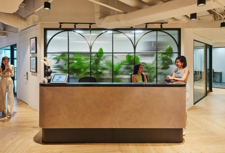 Reception area at Hong Leong Building with a modern front desk and arched glass partitions with green plants.