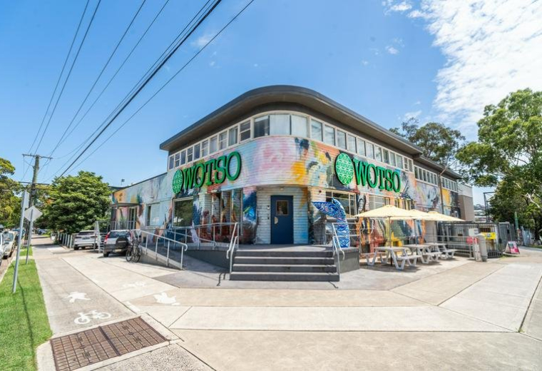 Main entrance of the WOTSO building featuring colorful wall murals and blue sky.
