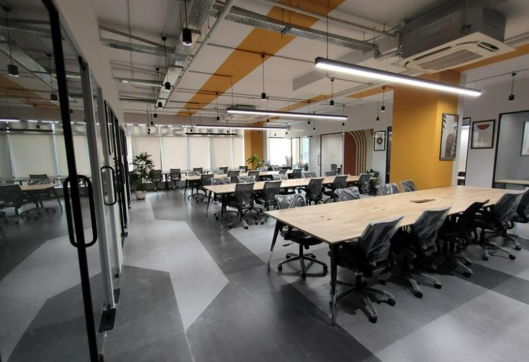 Spacious open-plan workspace at Pride Icon with large wooden communal desks and modern lighting.