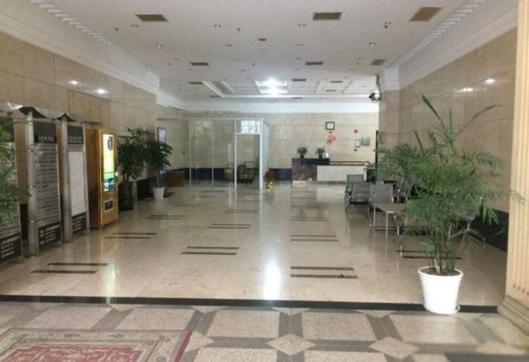 Spacious building lobby with polished marble floors and indoor potted plants.