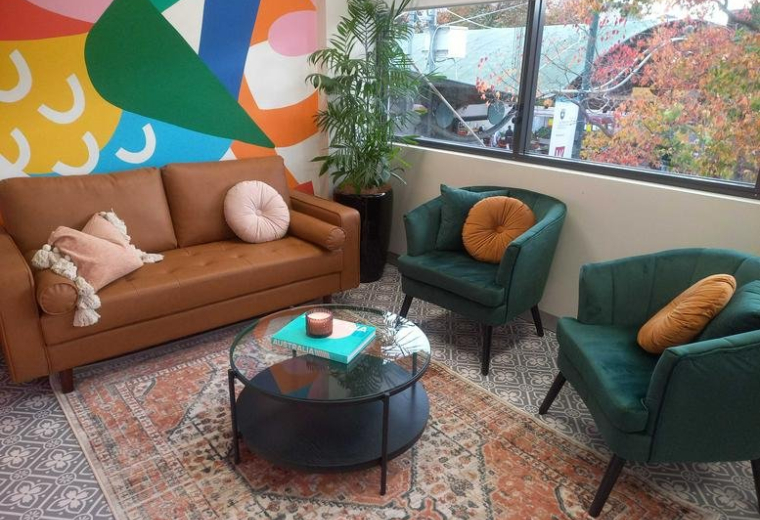 Lounge area with a tan leather sofa and colourful abstract mural at 244 Macquarie Street, Level 1.