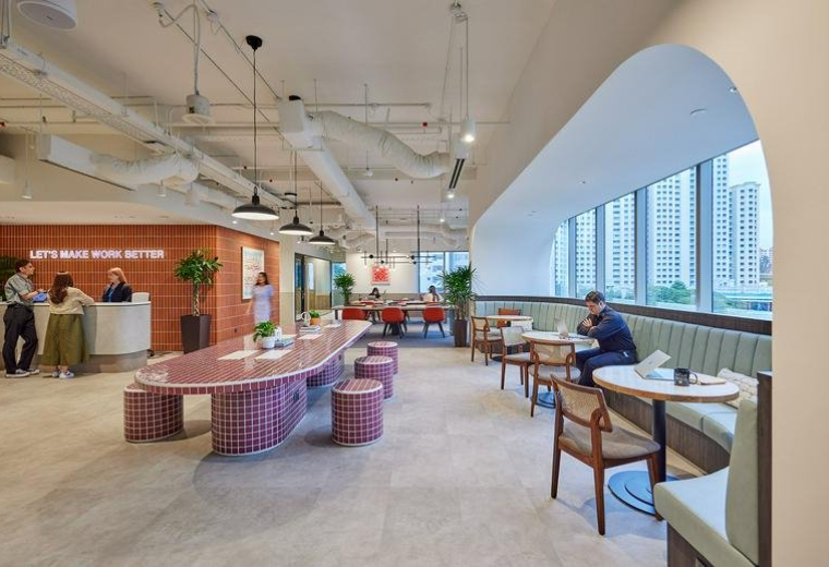 Spacious communal lounge and coworking area at Central Plaza with a long pink tiled table and arched windows.