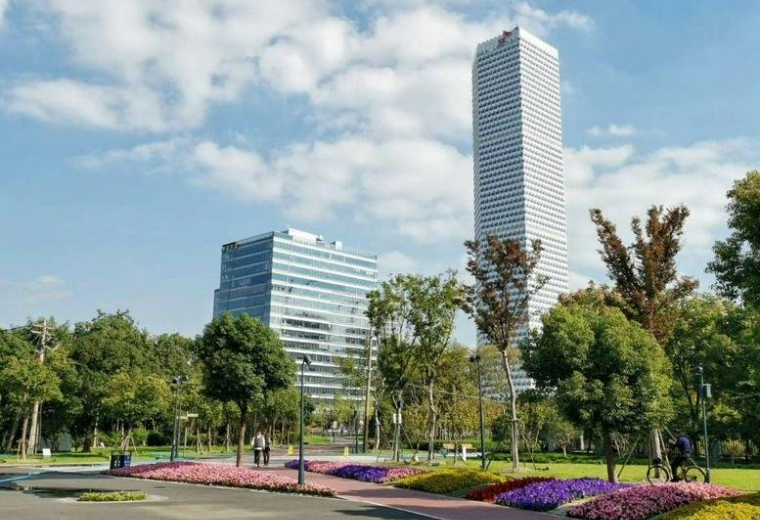 Exterior view of the towering glass facade of Building 1 at Global Metropolis Plaza next to a lush park.