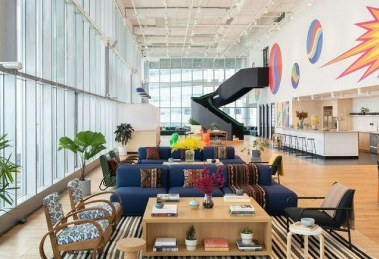 Spacious, sun-lit lounge at 30 Raffles Place with a striking black spiral staircase and colorful wall mural.