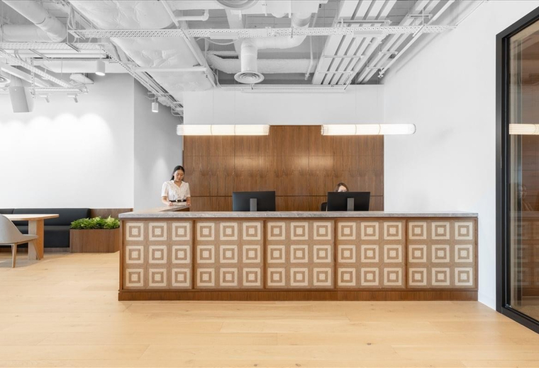Reception area at Hysan Place with a patterned wooden front desk and bright overhead lighting.