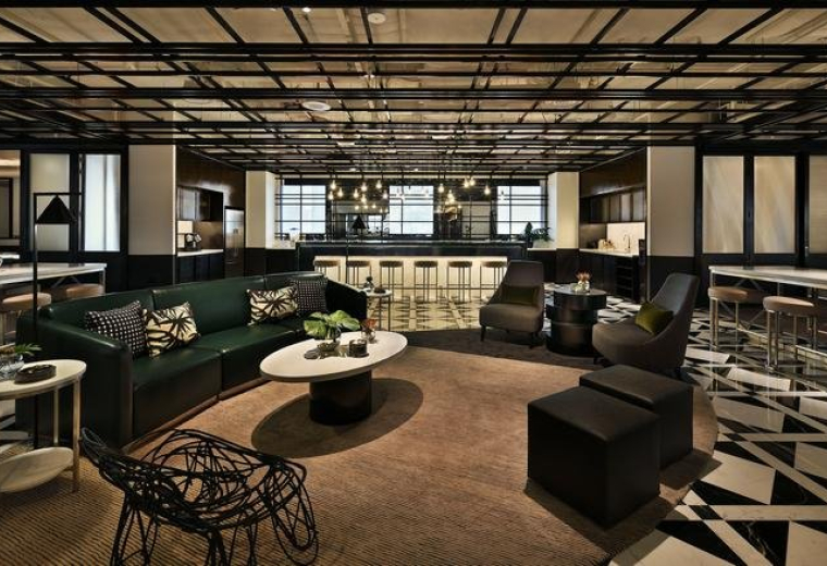 Spacious communal lounge at Ngee Ann City Tower B with dark green velvet sofas and a stylish patterned floor.