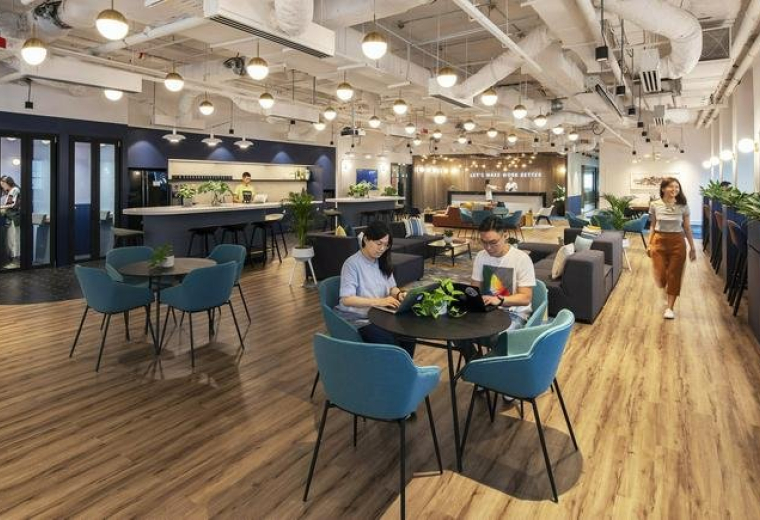 Spacious coworking area at OCBC Centre East with warm wood floors and vibrant blue seating.
