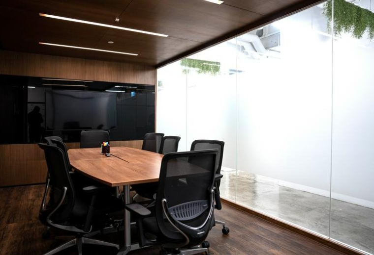 A professional meeting room at 5th Floor United Centre featuring a wooden table and black mesh chairs.