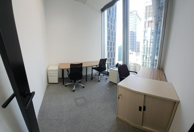 Interior view of a small office with two desks and large windows.