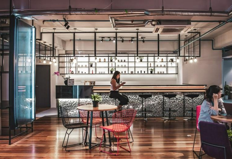 A stylish breakout lounge at Sekitar 26 Enterprise featuring a bar counter and vibrant red dining chairs.