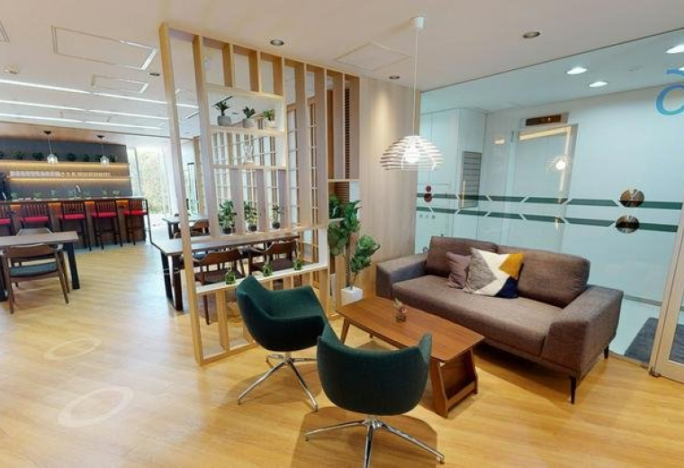 Spacious communal lounge at Ebisu Green Glass Building with velvet chairs and a wood-slat partition.
