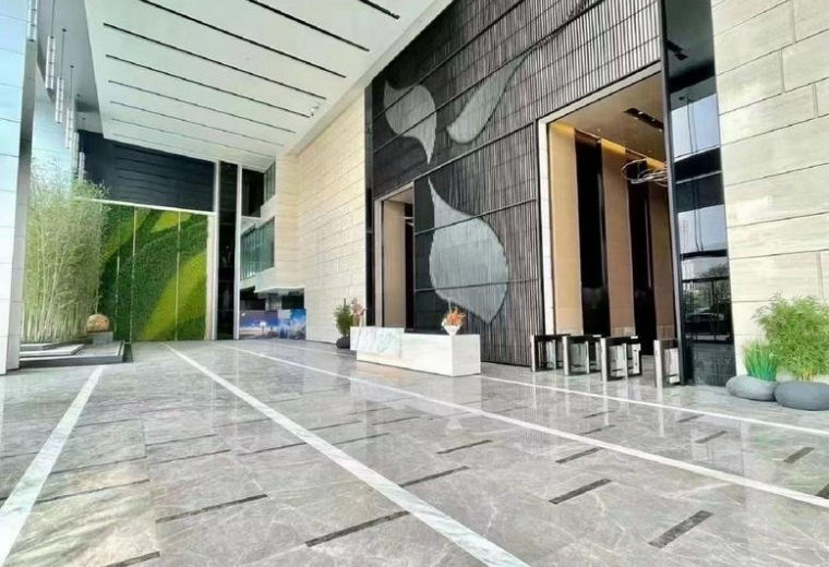 Spacious modern lobby with a decorative leaf-patterned wall and polished stone floors.