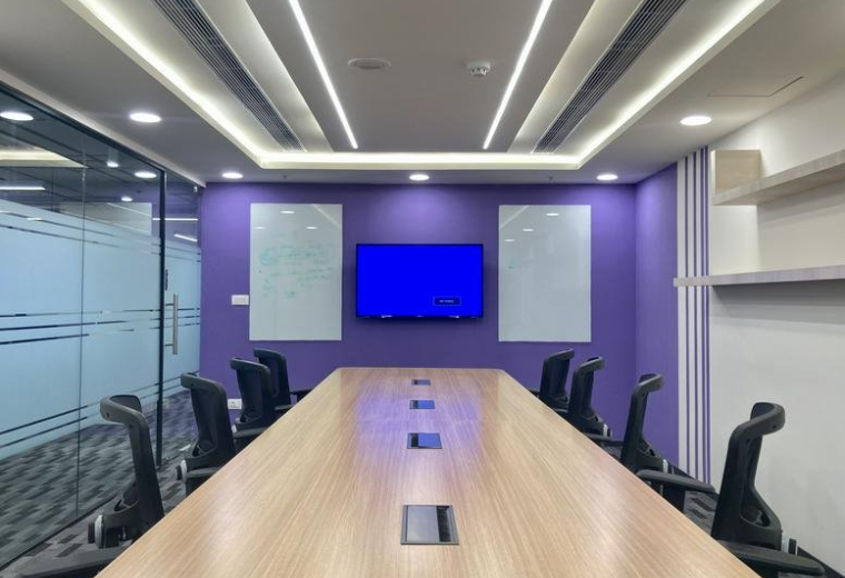 Spacious boardroom at iLabs Centre featuring a long wooden table, purple accent wall, and dual whiteboards.