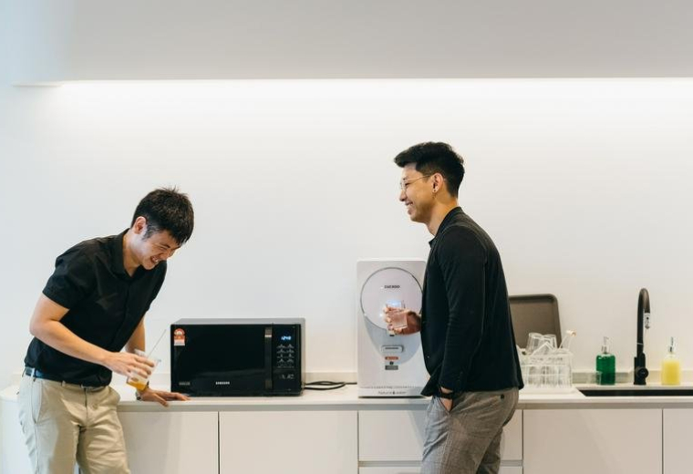 Communal break area with a kitchen counter, microwave, and people chatting at Southern Tower First Subang.