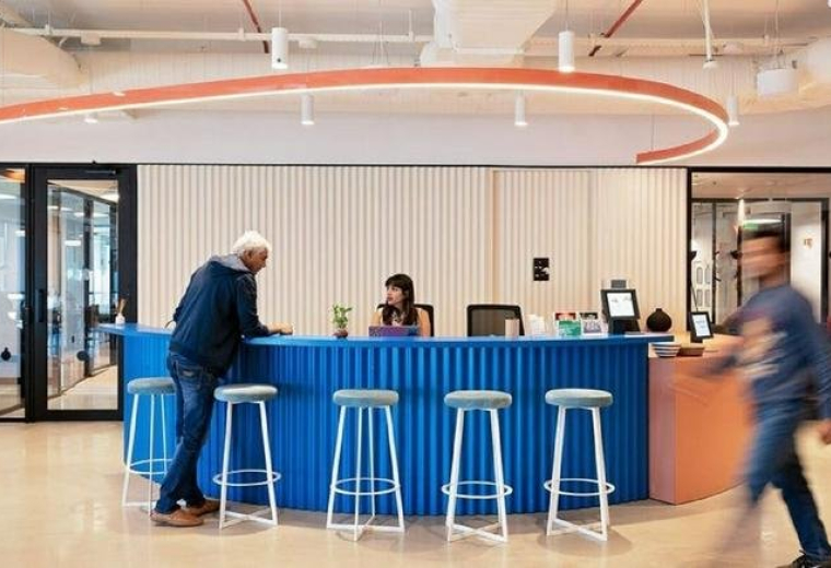 Reception area at Building No. 9, KRC Mindspace, with a vibrant blue desk and curved overhead lighting.