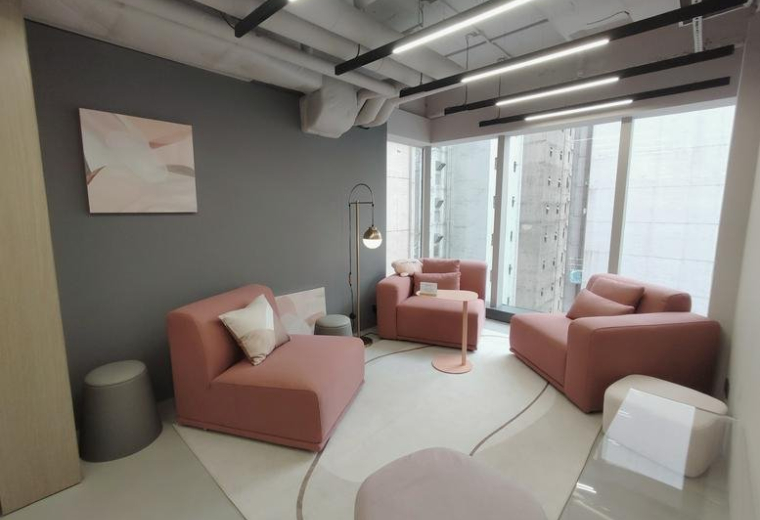 Stylish breakout area with pink modular sofas, a grey accent wall, and contemporary linear lighting.