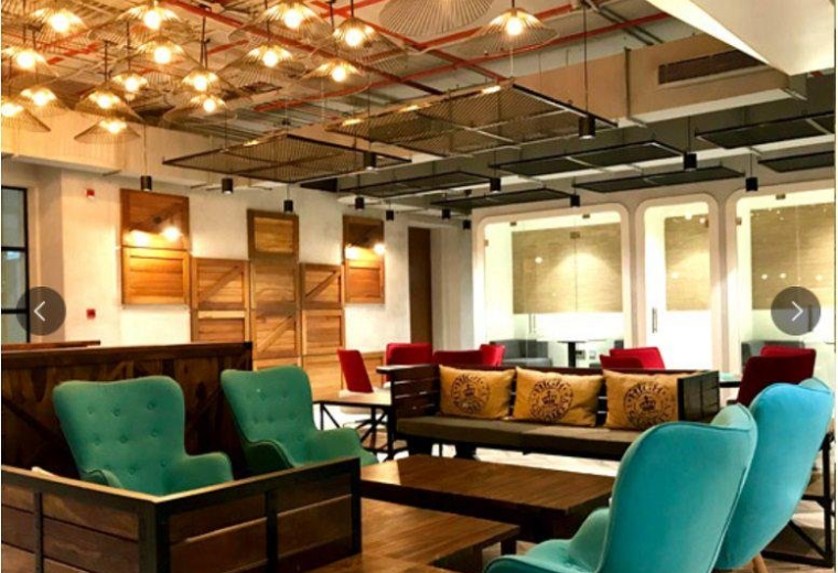 Spacious communal lounge at L3 Sreshta Marvel Sy. No. 136 with teal armchairs and warm decorative lighting.