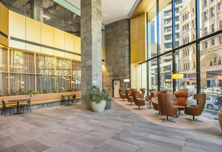 Spacious sunlit lobby of M/30, Pirie Street with stone floors and leather lounge chairs.