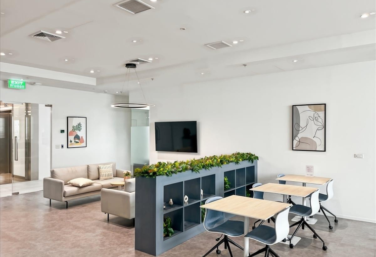 Lounge area at WHA Tower with comfortable sofas, a media wall, and stylish grey shelving units.