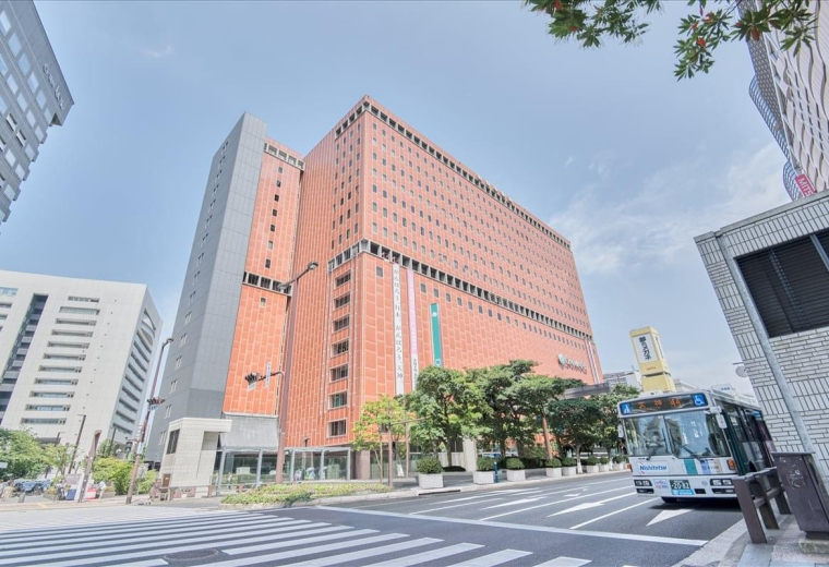 Exterior view of the red-brick Nishinihon Shinbun Building16F on a clear day.