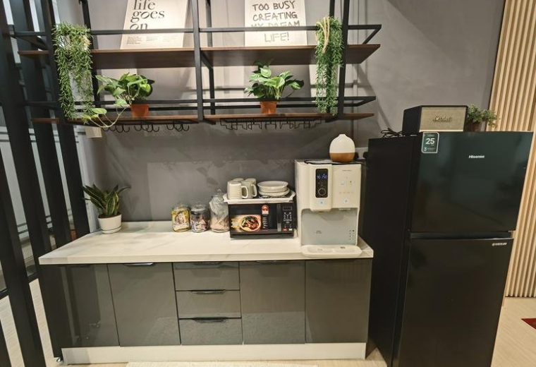 Kitchenette area featuring a grey cabinet, water dispenser, and wall-mounted shelving.