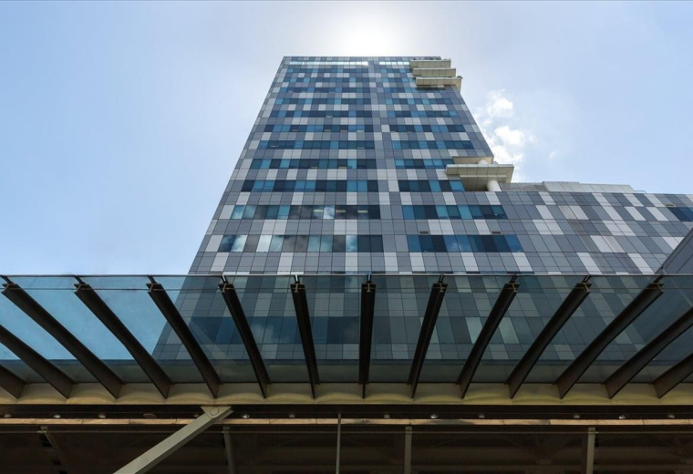 Low-angle exterior view of the glass-facade Galaxis 1 building against a bright sky.