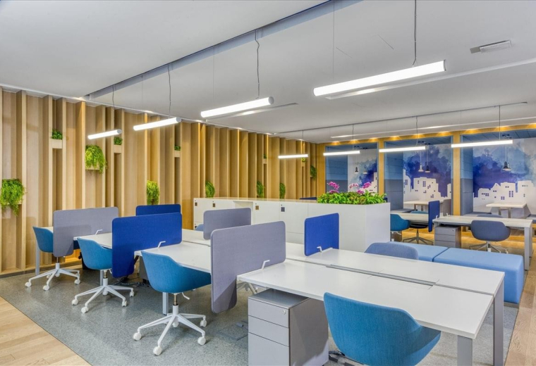 Spacious open-plan workspace at Guoco Tower featuring modern blue chairs, white desks, and warm wood-slat walls.