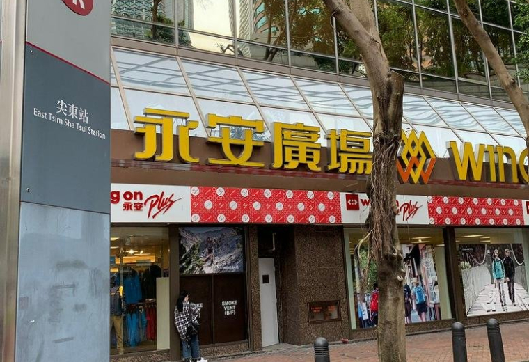 Exterior street-level view of Wing On Plaza building entrance with yellow signage and storefronts.