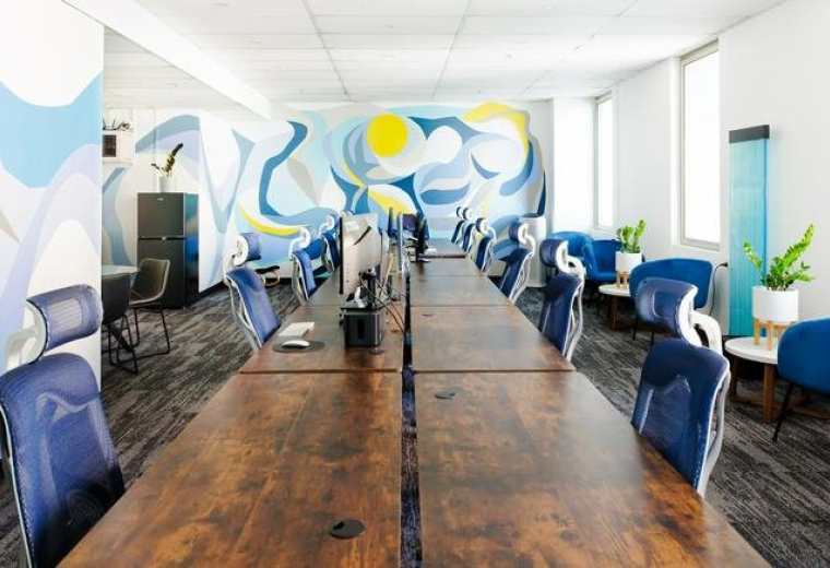 Spacious open-plan workspace at 117, King William Street featuring wooden desks and a vibrant blue mural.