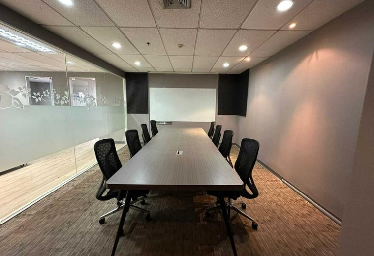 Spacious boardroom at SerMit Tower with a long table, mesh chairs, and a white whiteboard.