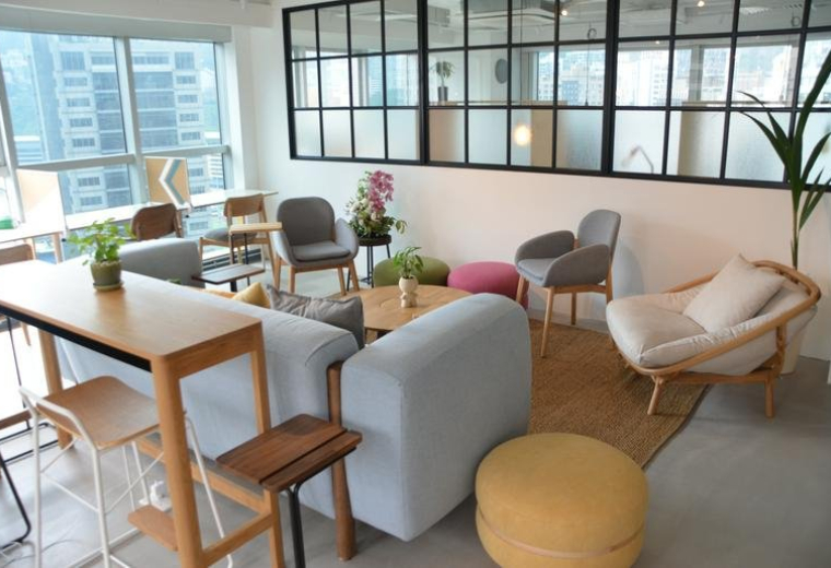 Bright communal lounge at Honest Building with eclectic seating, a blue sofa, and large windows.