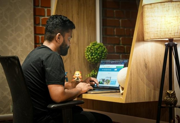 Person working at a laptop in a home office with warm lighting.