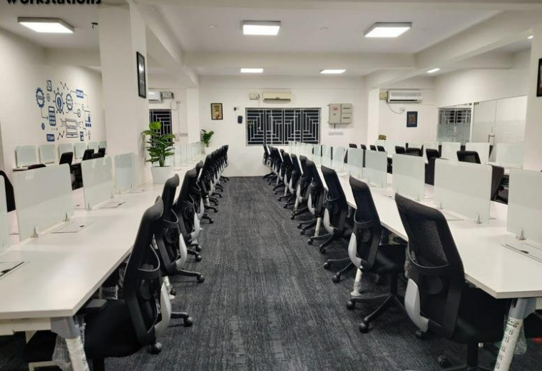 Spacious open-plan workstations at 320, Service Road featuring long white desks and black ergonomic chairs.