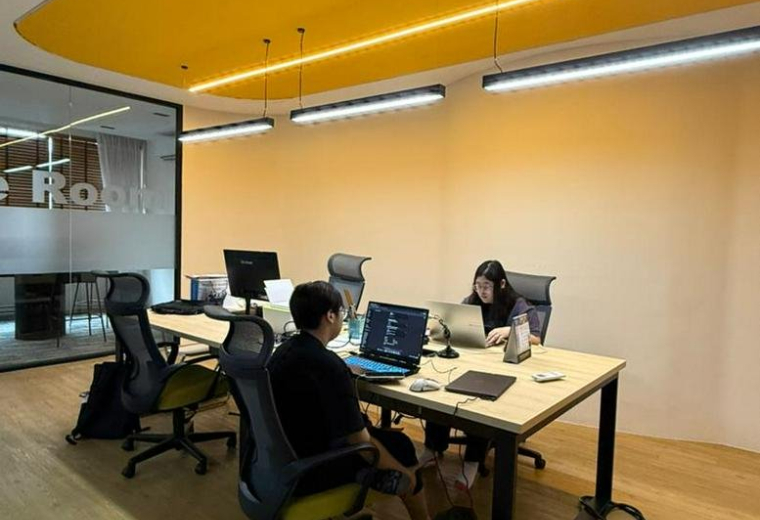 Interior view of a modern workspace with collaborative desks and yellow accents.