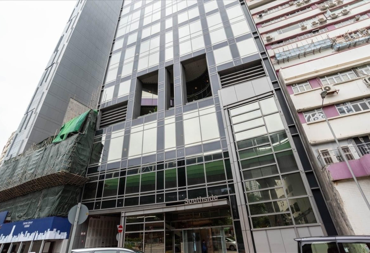 Spacious coworking lounge with diverse seating, wooden tables, and spherical pendant lighting.