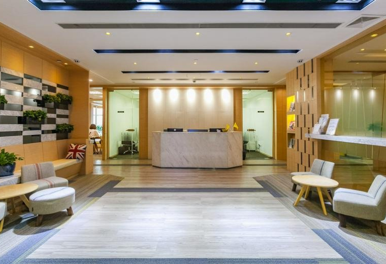 Bright reception lobby with a marble desk, wooden accents, and warm lighting.