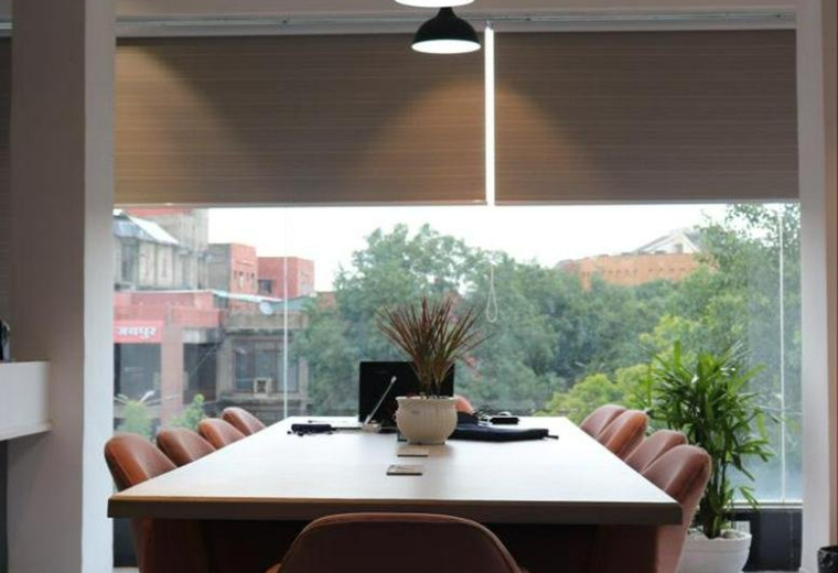 Spacious boardroom with a long white table, pink chairs, and modern pendant lighting.