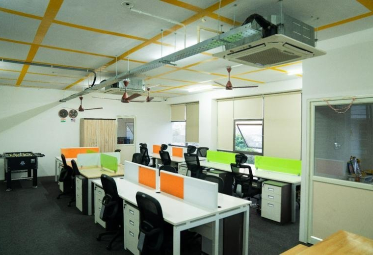 Wide view of the open-plan workspace at 70, Mallathahalli Lake Road with rows of desks and foosball table.