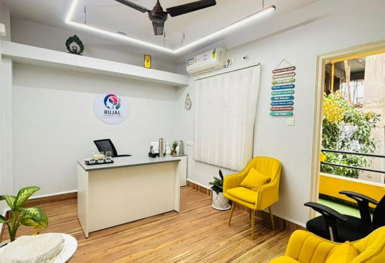 Reception area at 82/42 with a white desk, bright yellow armchairs, and warm wood-style flooring.