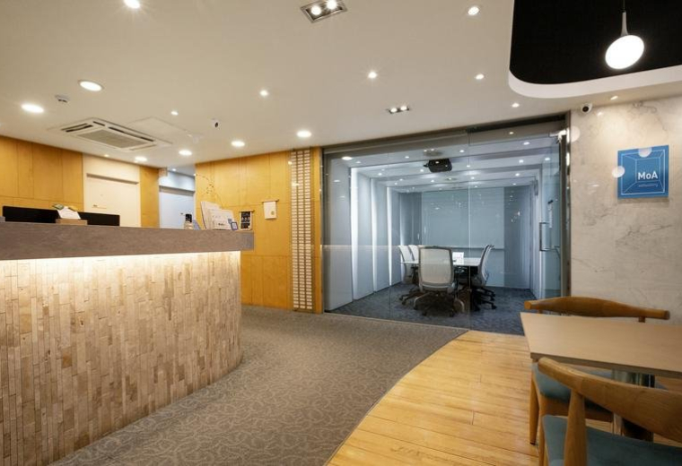 Bright reception area with a wood-paneled desk and glass meeting room.