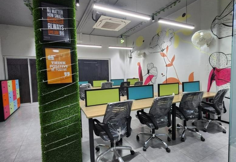 Open-plan coworking area at A-19A, Mayapuri Industrial Area with modern desks and vibrant wall art.