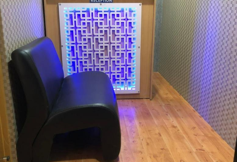 Reception area at The Bloom Co-Work with a glowing geometric desk and comfortable black seating.