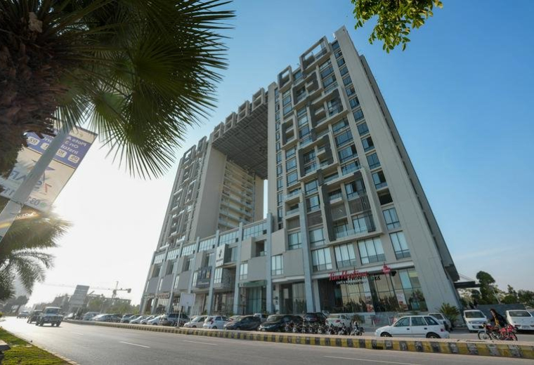 Low angle exterior view of the modern AJ Towers building with a distinctive central archway.
