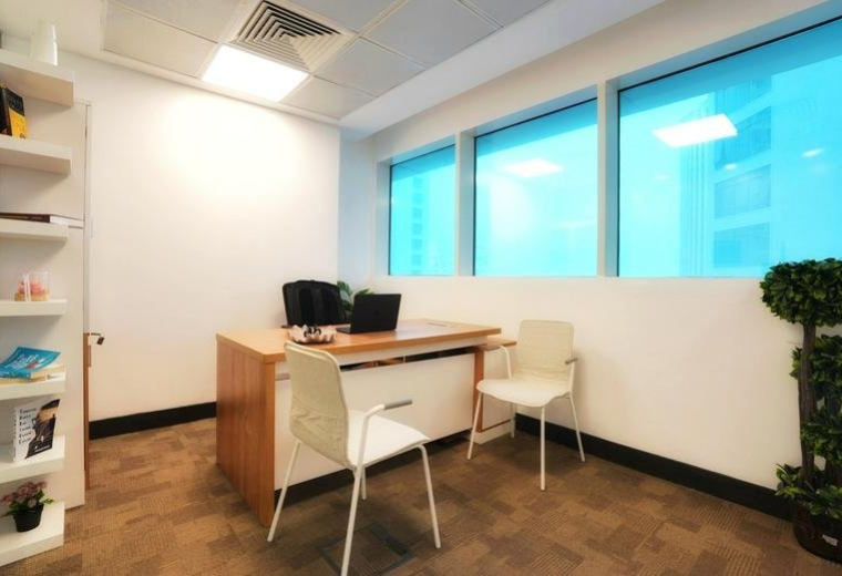 Bright private office at Al Jazzera with wooden desk, white chairs, and large windows.