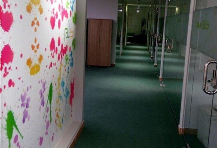 Corridor at Al Sahafa, King Abdul Aziz Road with a colorful paint-splatter feature wall and green carpet.